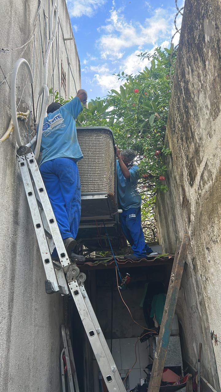 Equipe da Forte içando condensadora em acesso estreito entre prédios